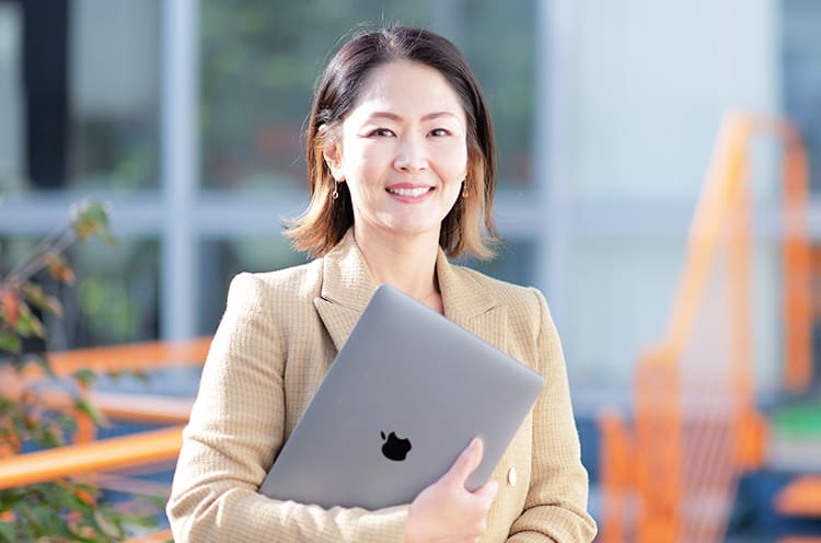 江口ゆきさんが笑顔でパソコンを持っている写真