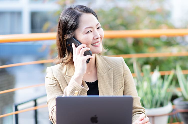 江口ゆきさんが笑顔で電話をしている写真