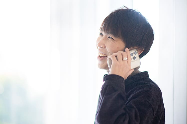 天間悠太さんが笑顔で電話をしている写真